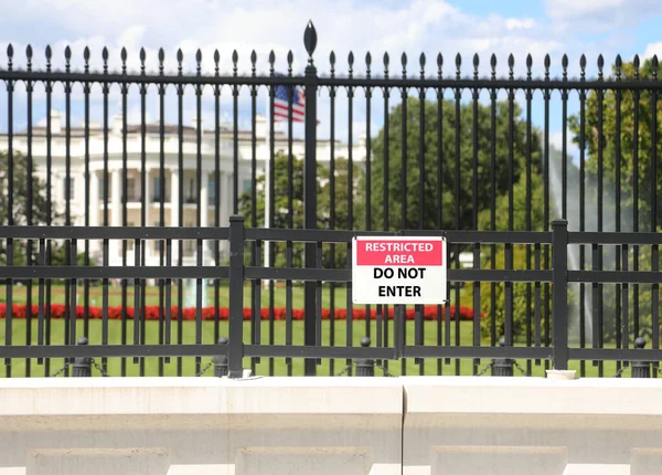 Washington, DC, ABD - 26 Ağustos 2025: Önünde alarm işareti olan büyük Amerikan bayrağı ve çiti olan beyaz ev