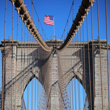 Brooklyn Köprüsü 'nün tepesinde Amerikan Bayrağı ve ABD' nin New York şehrinde birçok çelik kablo.