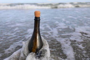 İçinde gizli bir mesaj ya da deniz kenarında bir hazine haritası bulunan mantar tıpası olan yeşil cam şişe.