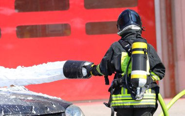 Oksijen tüplü itfaiyeci acil durum sırasında yangını köpükle söndürürken...
