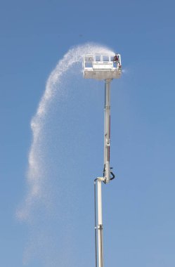 İtfaiye arabasının entegre yangın musluğuyla dolu sepeti su ve kendi kendine söndüren köpük maddesiyle birlikte aşağıdan ve mavi gökyüzünden görüldü.