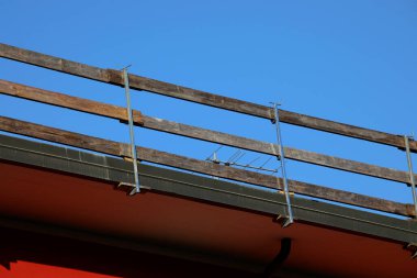 Dayanıklı koruyucu bariyerin ahşap kalasları işçilerin güvenliği için sıkıca yerleştirildi. Dairenin çatısında bakım sırasında insanlar olmadan düşmesinler diye.