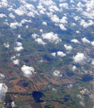 Toprağa gölge düşüren beyaz bulutlu tarlaların ve köylerin havadan görünüşü