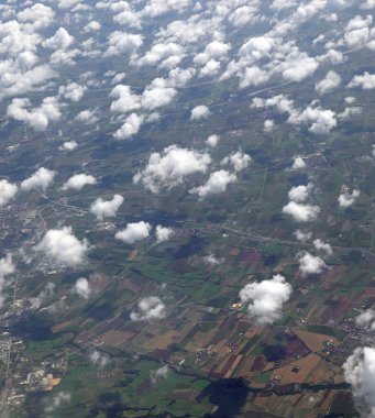 Aerial view of cultivated fields and villages with many small white clouds