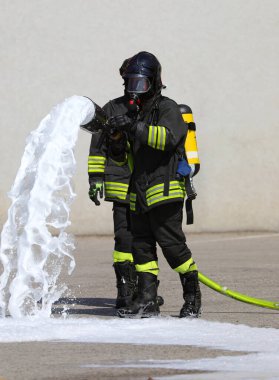 Acil durum sırasında oksijen tüplü itfaiyeciler köpüklü yangın hortumuyla yangın söndürüyorlar.