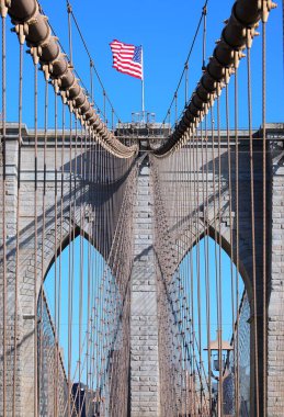 Brooklyn Köprüsü 'nün tepesinde büyük Amerikan Bayrağı New York' ta çelik kablolar ve güneşli bir günde mavi gökyüzü.