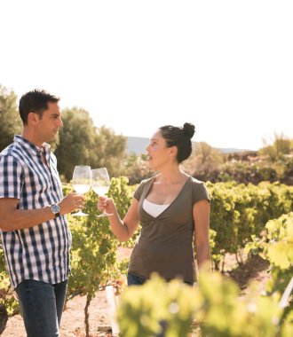 Beyaz gökyüzü güneşli bir günde rahat giysiler giyiyor üzüm bağları, şarap içme kadın ve erkek