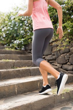 Pembe topaç, gri pantolon ve spor ayakkabısı gri taş basamaklardan çalıştıran giyen kadın