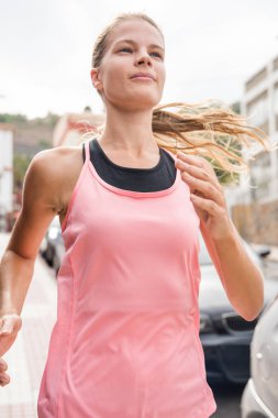 Pembe bir çalışan üst altında siyah bir gömlek giymiş bir sokakta çalışan genç bir kız görünümünü kapat