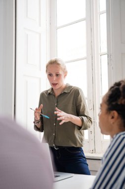 El hareketi ve bilgisayar önünde ona bakarak onun elinde kalem tutan bir resepsiyon önünde duran kadın