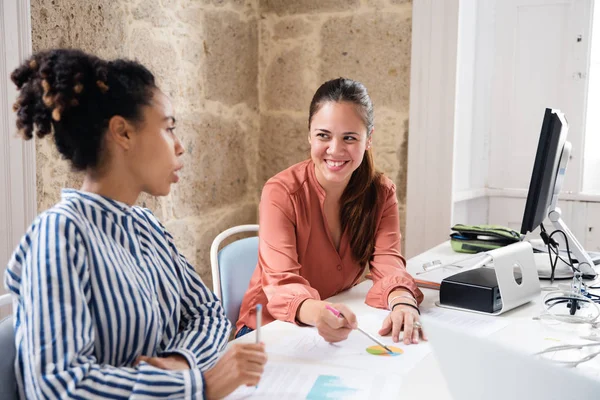 Duas Mulheres Escritório Conversando Rindo Enquanto Sentam Uma Mesa Com — Fotografia de Stock