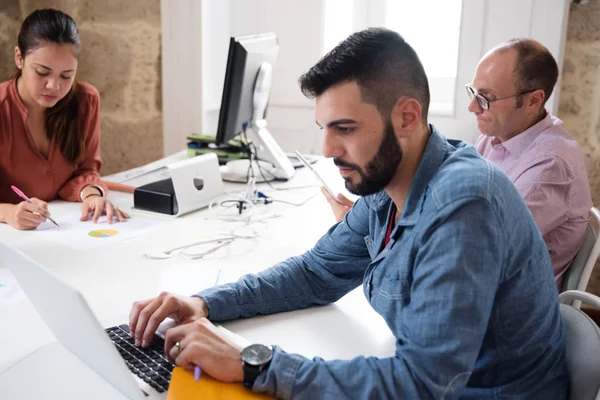 Three Colleagues Sitting Desk Working Female Writing One Male Reading — Stock Photo, Image