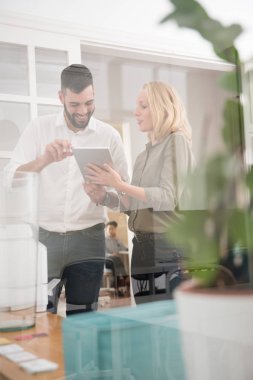 Erkek ve kadın bir ofis ortamında bir pc tablet tutar olarak gülümseyen,--dan a açık cam pencere dışarıda görünümdür
