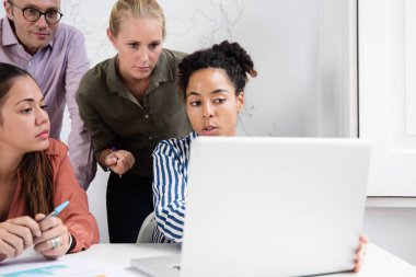 İş takım toplama çevresinde bir dizüstü bilgisayar ve içerik çalışma olarak ekrana bakarak