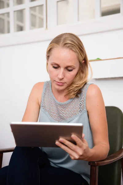 Frau Blickt Auf Ein Tablet Während Sie Einem Stuhl Vor — Stockfoto