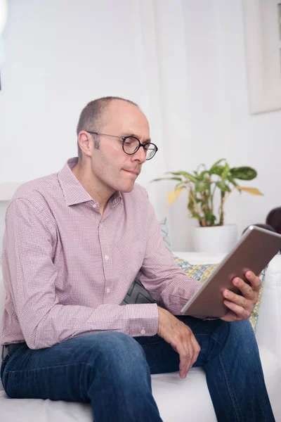 Man Purses His Lips Holds Tablet One Hand While Reading — Stock Photo, Image