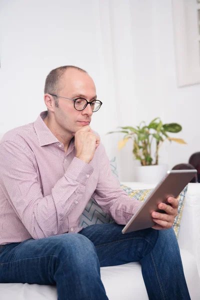 Man Has His Hand His Chin Reads Tablet Holding While — Stock Photo, Image