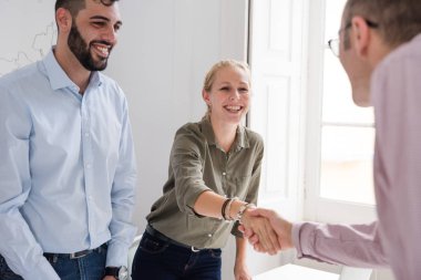 Erkek ve kadın üzerinde bir tablo ve gülümseme birbirimize el sıkışan bir ofiste