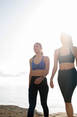 İki kadın rayları ile arka planda okyanus plaj boyunca yürüyüş