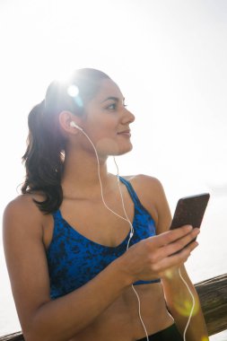 O cep telefonunu takılı kulak telefonları için dinler gibi tarafına arayan kadın