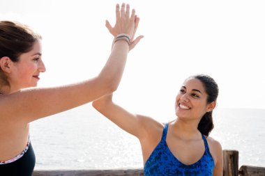 İki kadın egzersiz bitirdikten sonra sahilde bir beşlik yapıyor yakın çekim