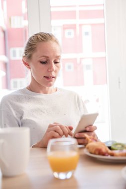 Cep telefonuna baktığını ve screen tuşuna basıldığında bir kahvaltı masasında oturan kadın
