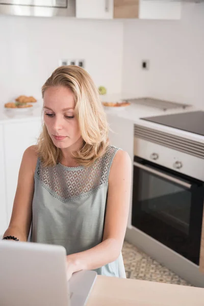 Mujer Rubia Sentada Una Mesa Una Cocina Escribiendo Ordenador Portátil — Foto de Stock