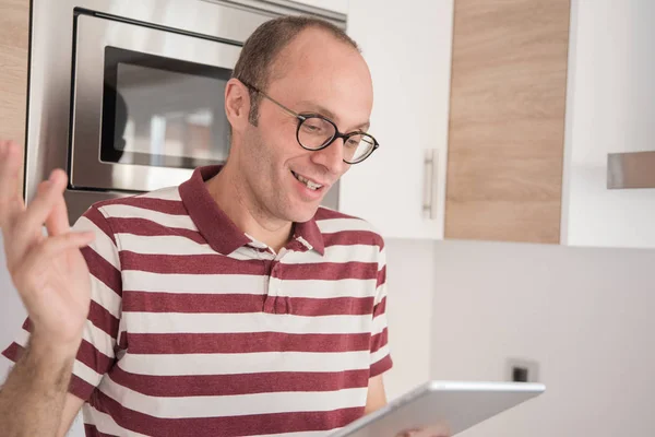 Man Holds His Hand Smiles Looks Tablet While Standing Kitchen — Stock Photo, Image