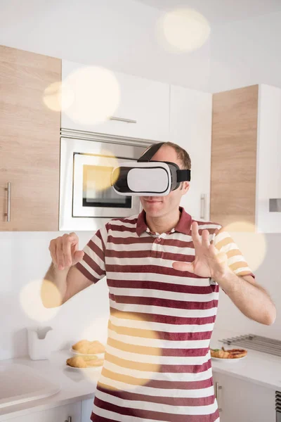 男子站在厨房使用虚拟现实的眼镜 并举行了他的手 — 图库照片
