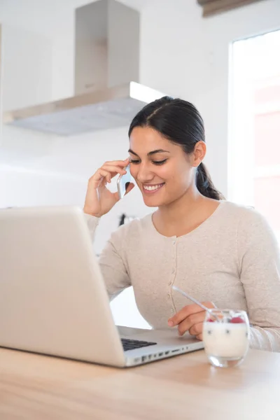 Beszél Cell Phone Lenézett Mosolyogva Egy Asztalnál Egy Laptop Előtt — Stock Fotó