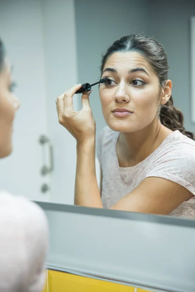 Woman Applies Mascara Her Upper Lashes She Looks Directly Mirror — Stock Photo, Image