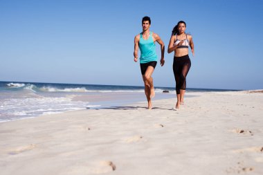 Arkadaşlar uzakta dalgalar ve mavi gökyüzü ile bir yaz gününde beyaz kumlu plajda birlikte çalışan