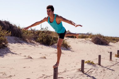 O bir bacak üzerinde bir kutup üzerinde dengeler gibi öne eğilerek genç adam ve kararlı himeslf kollarını kullanır