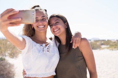 İki bin yıllık kız gülümseyerek ve bir cep telefonu tutun ve kendilerini selfie çekmek gibi gülüyor