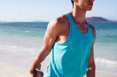 Sahilde egzersiz ve bacağını tutarak genç bir adam yakın