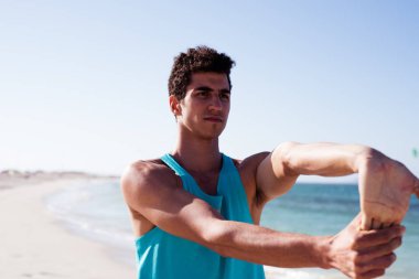 Mavi gömlekli ve koyu saçlı, elleri önünde bağlı bir adamın yakını