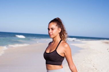 Genç kadın o egzersizleri ve okyanusa bakar gibi kollarını arkasında gerilmiş ile ileriye bakıyor