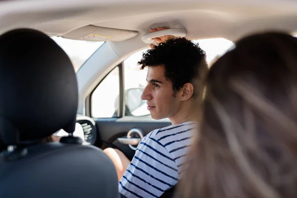 stock image Young man looking out of the car window of the car he is sitting in, he is wearing a stripped shirt