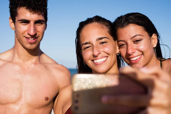 一群年轻人对着镜头微笑 他们站在沙滩上拍照 — 图库照片
