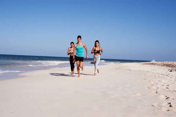 Trzy Młode Osoby Biegną Białej Piaszczystej Plaży Przy Oceanie — Zdjęcie stockowe