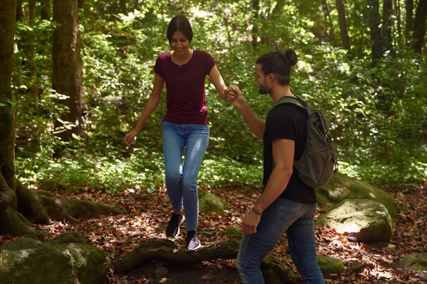 El hombre ayuda a una mujer a caminar sobre un árbol caído — Foto de Stock