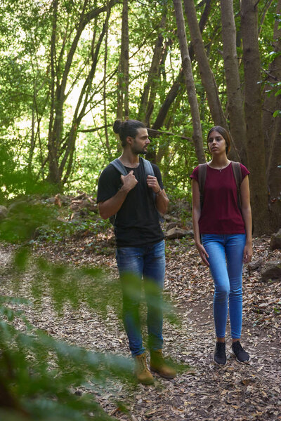 Young couple strolling in a leafy green forest, talking