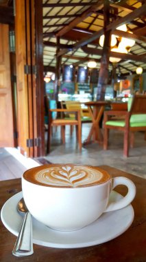 Ahşap masa üzerinde fincan sıcak kapuçino kahve. Cappuccino espresso kahve ile karışık, süt ince bir köpük ve süt basınçlı buhar. Bazen kahve tarçın tozu veya kakao tozu ile süslenmiş.