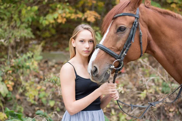 Mladá, blond dívka pózuje s koněm, krásná dívka a silné koně. — Stock fotografie