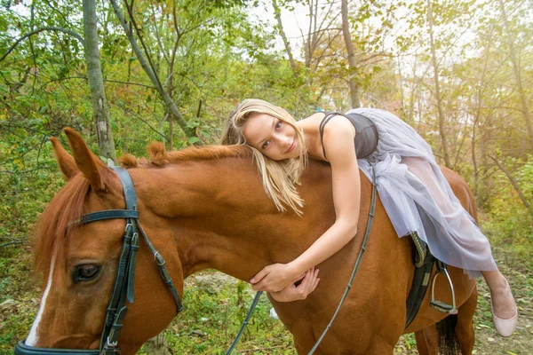 Uma jovem, menina loira posando com um cavalo, uma menina bonita e um cavalo forte . — Fotografia de Stock