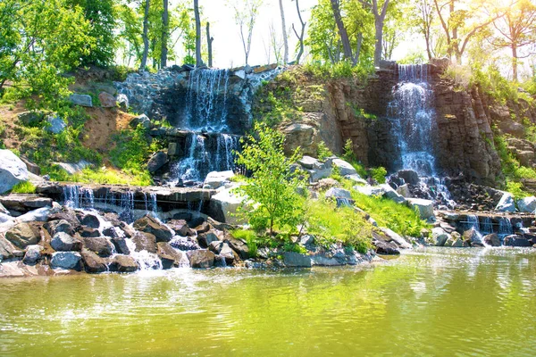 Beautiful waterfall under sunlight, many beautiful water jets surrounded by green forests. — Stock Photo, Image