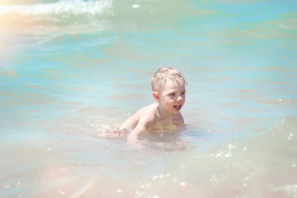 Маленький мальчик плавает в море, бежит и брызгает в волнах чистой . — стоковое фото