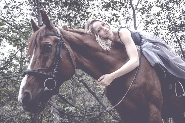 Молода блондинка позує з конем, красивою дівчиною і сильним конем . — стокове фото