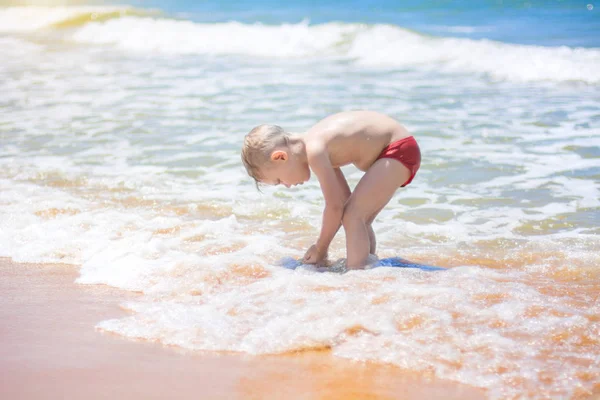小さな男の子を実行し、純粋な波のしぶき、海で泳いで. — ストック写真