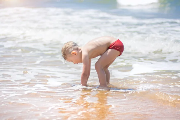 Úszhat a tengerben, futás és hullámok tiszta fröccsen kisfiú. — Stock Fotó